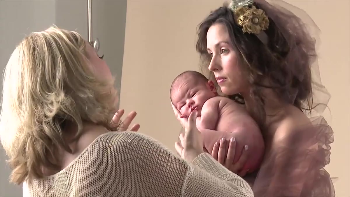 Photographer guiding mother&rsquo;s chin down toward baby&rsquo;s head