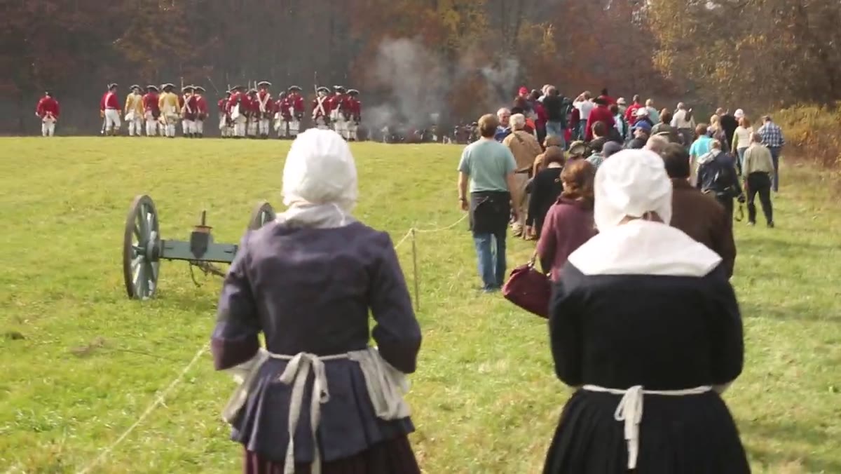 Reenactment soldiers in uniform with black powder smoke, shot from sidelines